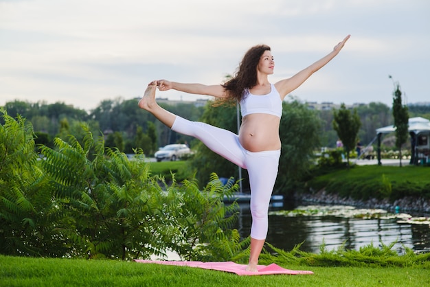 Pregnant woman doing prenatal yoga on nature.