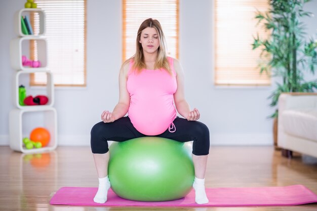 Беременная женщина делает йогу на осуществление мяч