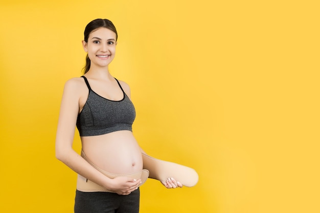 беременная женщина одевает ремень для беременных
