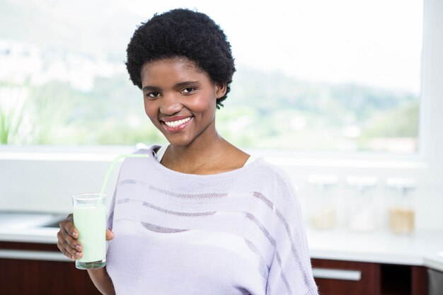 Pregnant woman drinking a glass of milk in kitchen