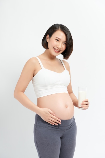 白い背景の上の牛乳を飲む妊婦。