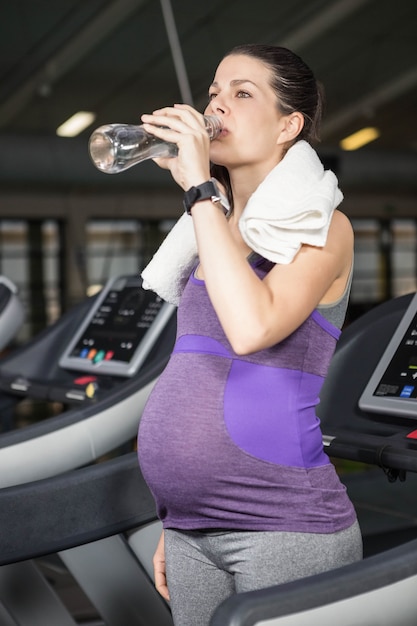 Pregnant woman drinking water in the gym