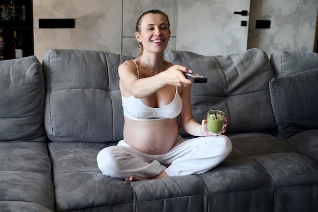 Pregnant woman eating a smoothie in the living room Healthy pre