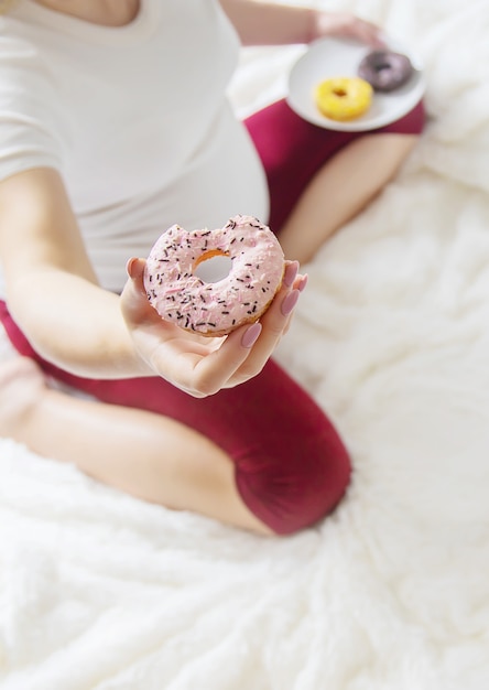 A pregnant woman eats sweet donuts. Selective Focus.