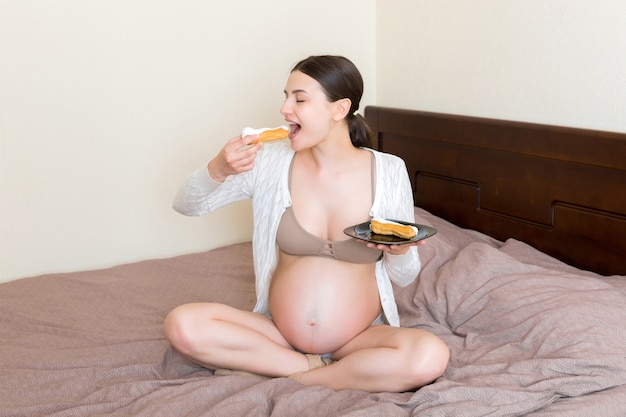 妊娠中の女性はおいしいケーキを食べることを楽しんでいます