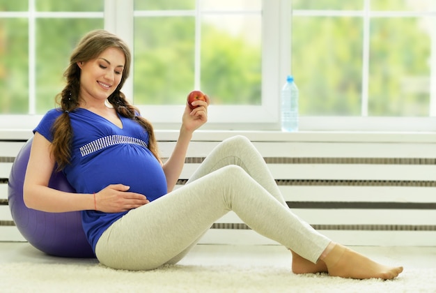 Pregnant woman exercises with gymnastic ball at home