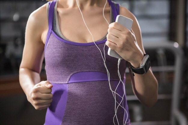 Pregnant woman exercising on a treadmill while listening to music