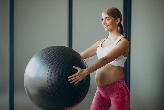 Беременная женщина тренируется с мячом в классе пилатеса