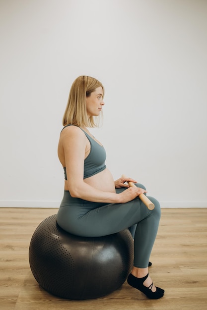 Pregnant woman exercising with the help of reformer on pilates class