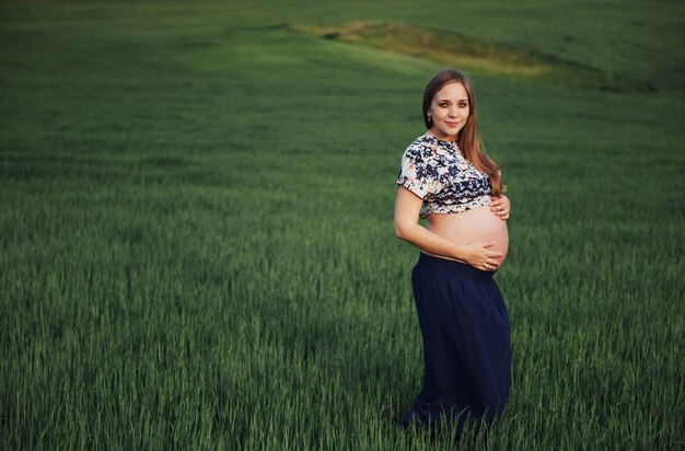 Pregnant woman in field of green wheat