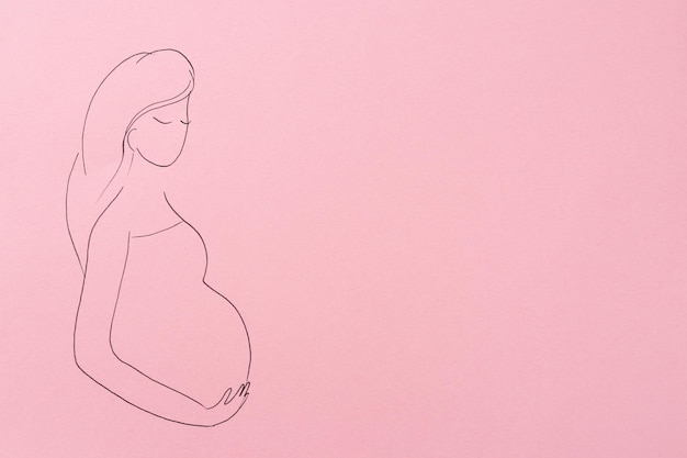 Photo pregnant woman figure drawn on pink background top view with space for text surrogacy concept