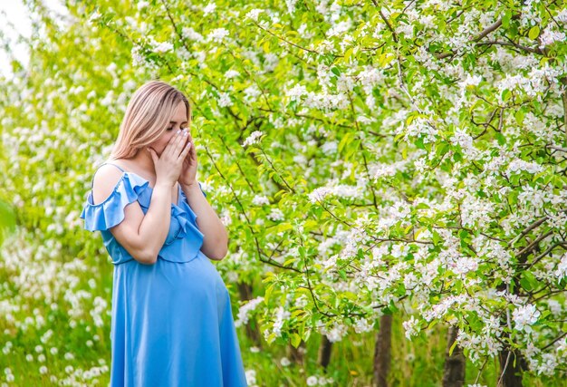 A pregnant woman in the garden of flowering apple trees is allergic Selective focus