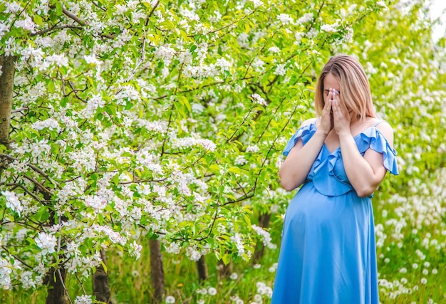 A pregnant woman in the garden of flowering apple trees is allergic Selective focus