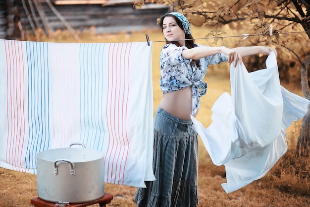 Pregnant woman hanging sheets on the rope for drying