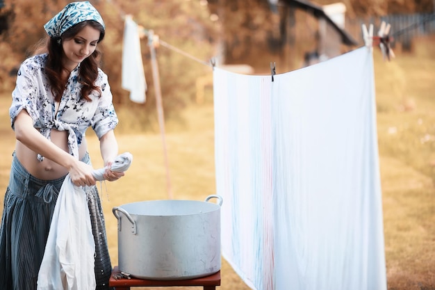 Pregnant woman hanging sheets on the rope for drying