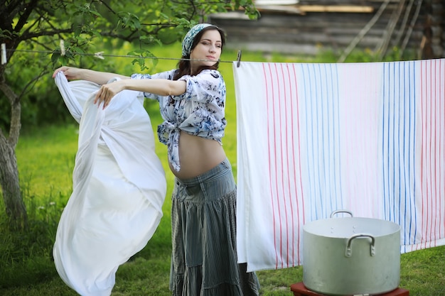 Pregnant woman hanging wash clothes on the rope for drying