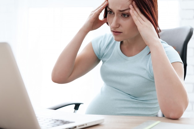 A pregnant woman has a headache in hand.