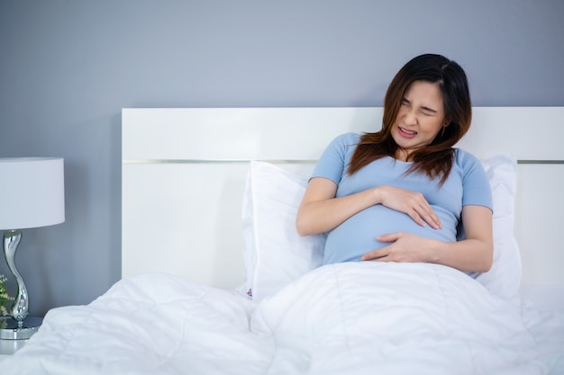 Pregnant woman has a stomachache on a bed