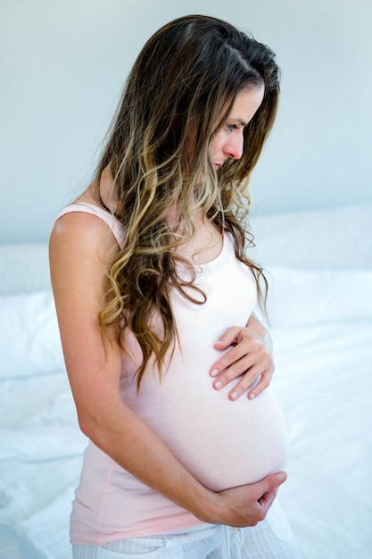 pregnant woman, in her bedroom, holding her bump