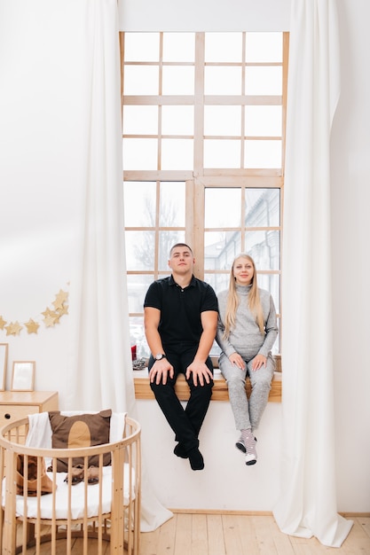 Photo a pregnant woman and her husband are waiting for the baby and sitting on a large panoramic window