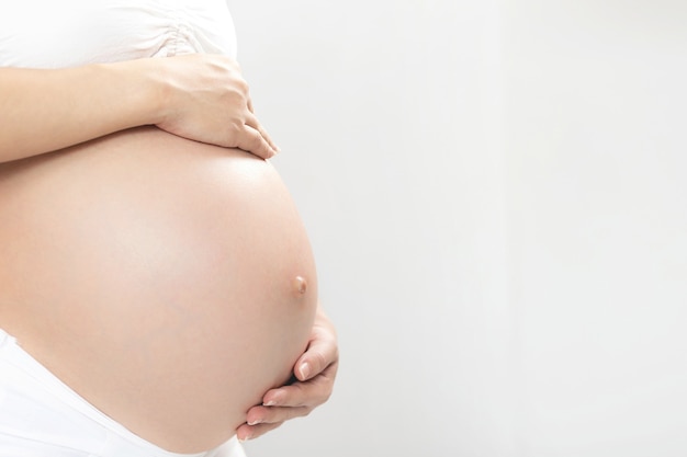 Pregnant woman and her husband hand splice hugging the tummy