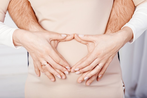 Pregnant woman and her husband holding hands on pregnant belly