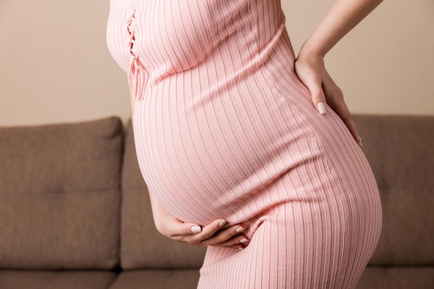 Pregnant woman hold back pain on sofa at thr home Maternity healthcare concept support products