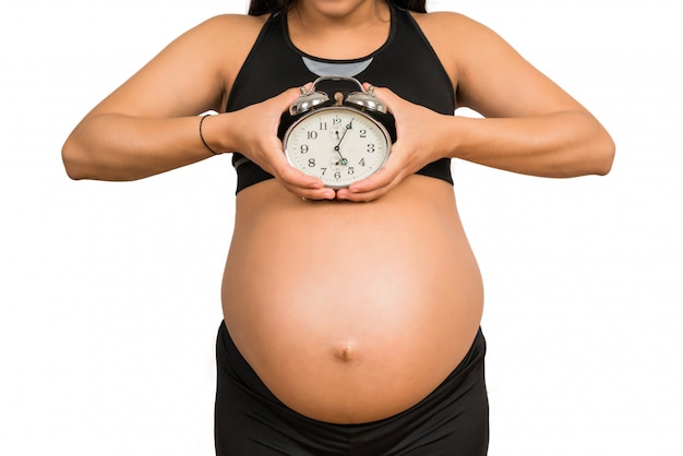 Pregnant woman holding alarm clock.