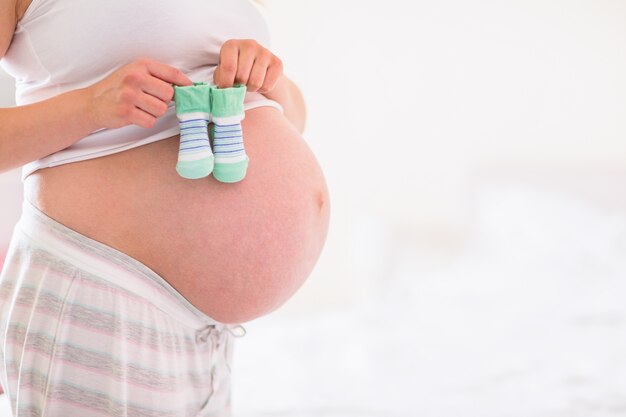 Pregnant woman holding baby shoes over bump