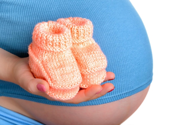Pregnant woman holding a beautiful woolen baby shoes