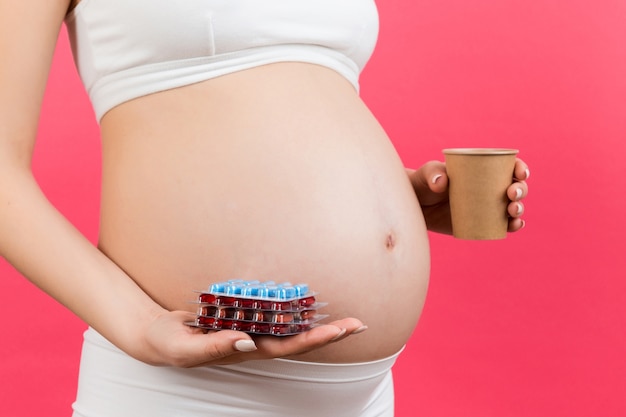 pregnant woman holding blisters with pills