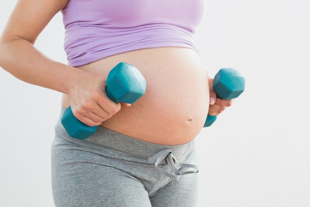 Pregnant woman holding dumbbells 