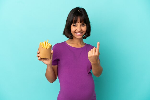 来たるジェスチャーをしている孤立した背景の上にフライドポテトを保持している妊婦