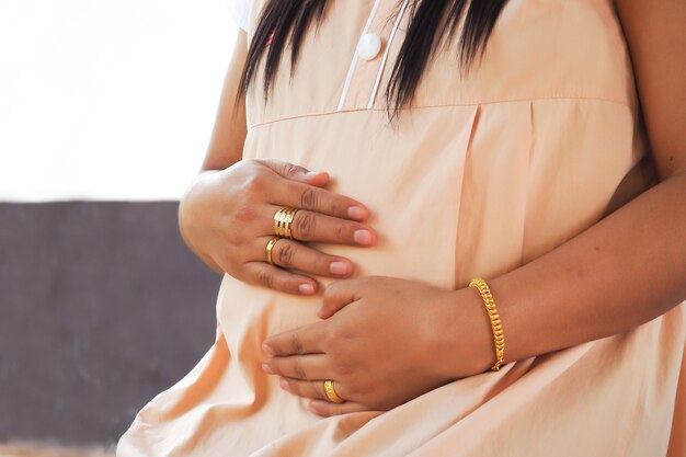 Pregnant woman holding hands to her belly. 