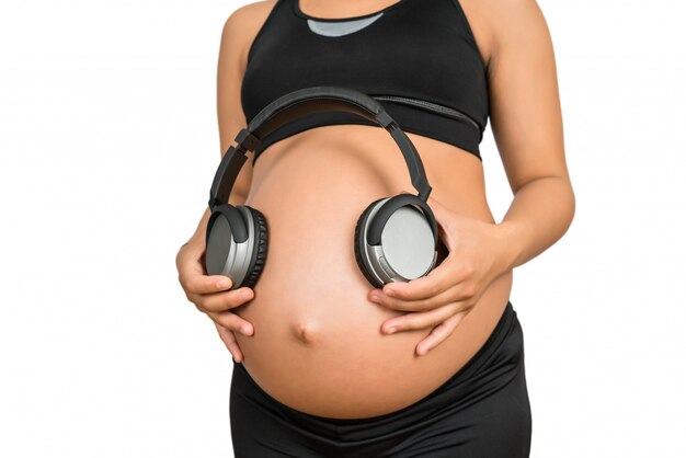 Premium Photo  Pregnant woman putting headphones on her belly concept of  listening music before birth