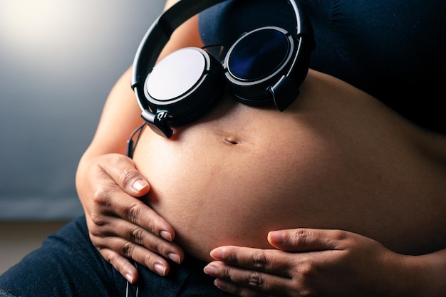 Pregnant woman holding headphones on her belly