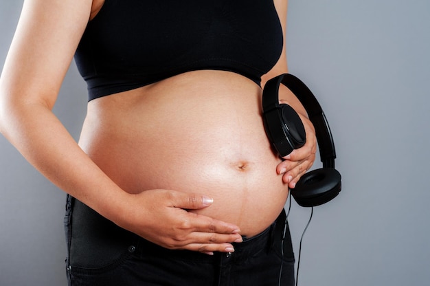 Pregnant woman holding headphones on her belly