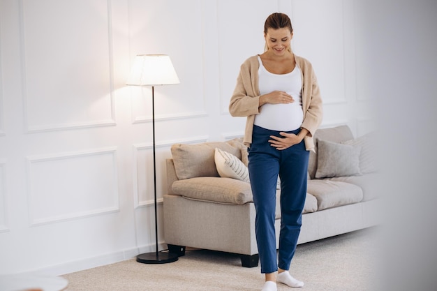 Pregnant woman holding her belly aqt home