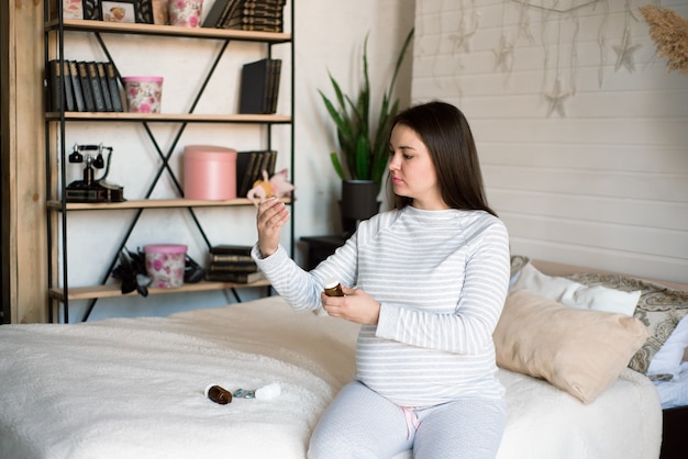 Photo pregnant woman holding medicine. girl holding pills in her hands.