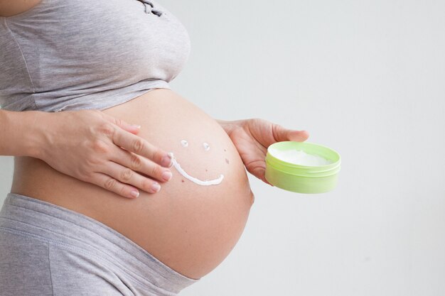 Pregnant woman holding red heart and hand on her belly, symbol of new life, concept of expecting for baby and extending family.