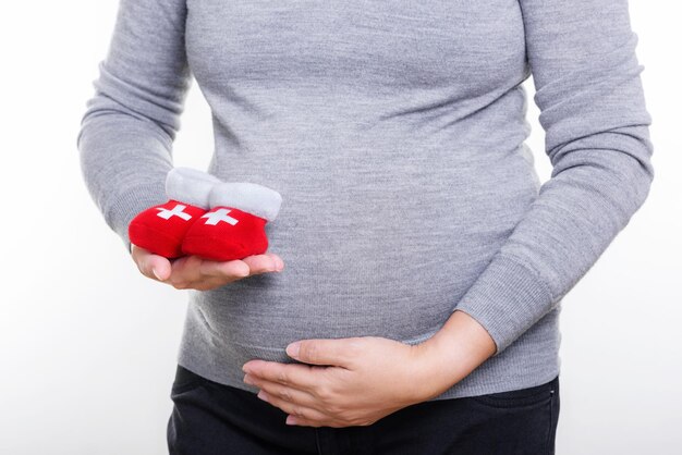 Pregnant woman holding red socks for baby