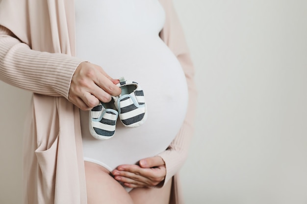 pregnant woman holding shoes for the newborn baby