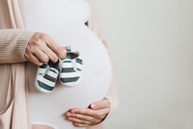 pregnant woman holding shoes for the newborn baby