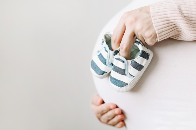 pregnant woman holding shoes for the newborn baby