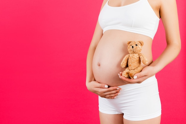 Pregnant woman holding a teddy bear