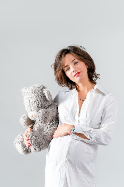Pregnant woman holding a teddy bear.
