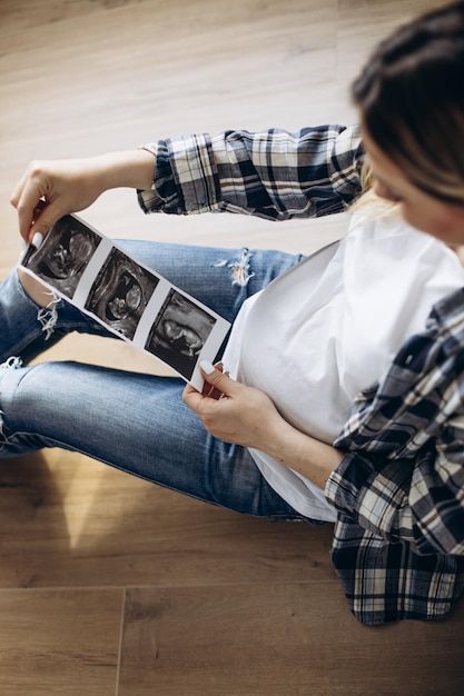 Pregnant woman holding xray photo of her future baby