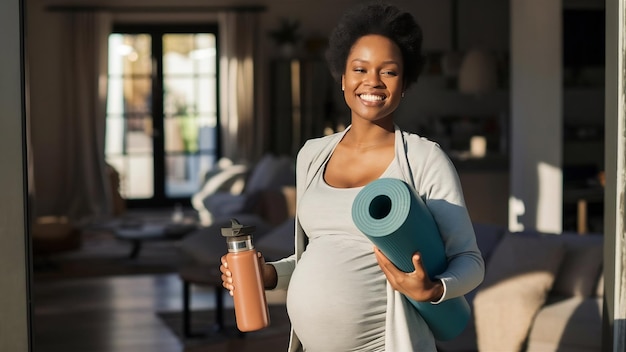 Pregnant woman holding a yoga mat and a reusable water bottle getting ready to exercise at home wel