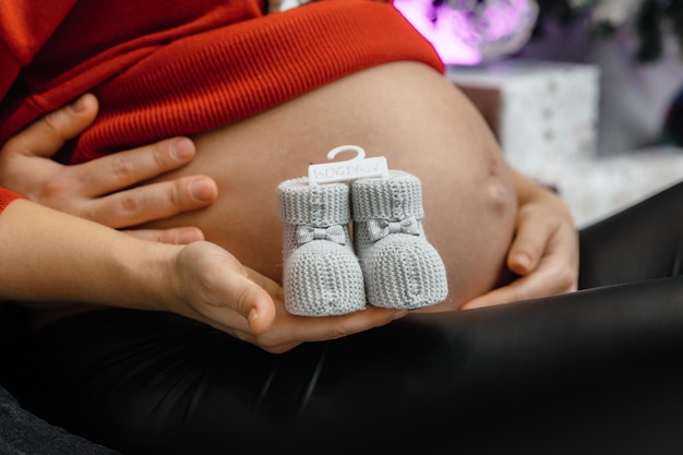 A pregnant woman holds a baby booties on her belly.