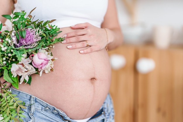 Una donna incinta detiene bellissimi fiori carino concetto sano gravidanzafesta della mamma